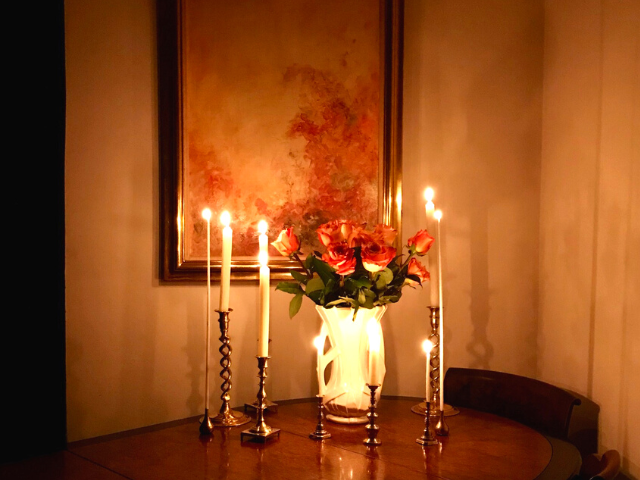 Roses and Lit candles on a table. Ruth's original painting in background.
